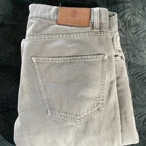 Grå jeans från Brunello Cucinelli - Snygga ljusgrå jeans från Brunello Cucinelli med slitna detaljer och klassisk femficksdesign. Jeansen är tillverkade i bomull med en skön känsla. Passformen är "Leisure fit" och har storleken 46 och motsvarar ungefär 32/32. Jeansen har två små hål i den ena fickan, som går att lätt reparera. Mer bilder finns i Privat mvh. 