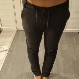 Svarta mjukisbyxor från Kappahl - Svarta mjukisbyxor från Kappahl med slim passform. Byxorna har snörning i midjan, knapp och bälteshällor samt fickor både fram och bak. Materialet är mjukt och stretchigt, perfekt för en chill och avslappnad stil.