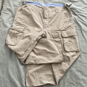 Beiga cargopants från D. Scandinavia - Snygga beiga cargopants från Dressman med flera stora fickor, dessutom två på sidorna. Perfekta för en chill och avslappnad stil. Klassisk passform och praktiska detaljer.