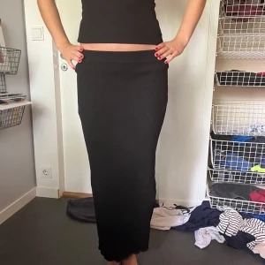 Svart kjol  - Svart långkjol i ribbat material med en snygg slits på sidan. 