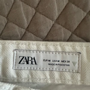 Vit jeanskjol från Zara med fransad kant - Vit jeanskjol från Zara i klassisk femficksmodell. Kjolen har fransad nederkant och slitna detaljer framtill för en cool, avslappnad vibe. Jag köpte den för ett år sedan fast har aldrig använt den.