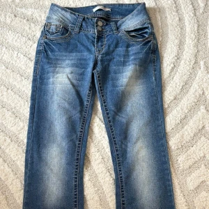 Blå jeans med broderade bakfickor - Snygga blå jeans från No Boundaries med coola broderade och dekorerade bakfickor. Jeansen har normal passform, dubbla knappar i midjan och klassisk femficksdesign. Materialet är jeans med slitningar framtill för en trendig look. Köpt på second hand för ett par månader sedan men i bra skick. 