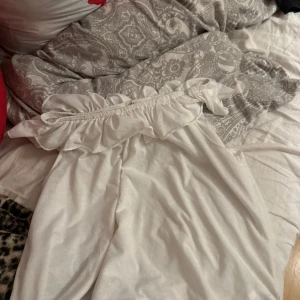 Vit volang tröja  från H&M - Supersöt vit volangtröja  från H&M med volangdetalj upptill och resår i midjan. Lätt och skön i bomull, perfekt för varma dagar. Enkel och stilren design som passar dig som gillar en clean look.