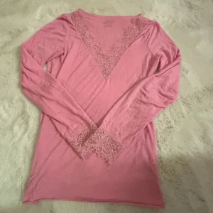 Rosa v-ringad tröja med spets Intimissimi - Supersöt rosa långärmad tröja från Intimissimi i ultralätt kashmirblandning. Djup v-ringning och ärmslut med fina spetsdetaljer som ger en romantisk vibe. Perfekt för dig som gillar mjuka material och snygga detaljer.