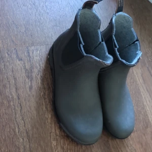 Svarta chelsea boots från Tretorn - Svarta chelsea boots från Tretorn. Tillverkade i slitstark syntet med elastiska paneler på sidorna och grov sula för extra grepp. Jättebra anpassad för regniga dagar och enkel att dra på med hällor baktill. Skorna är nya.
