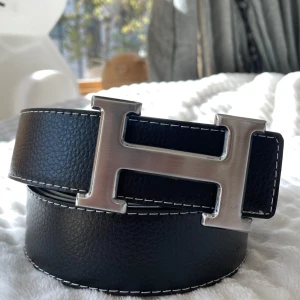 H Bälte - Säljer ett svart bälte med ett silvrigt snyggt ”H” spänne. Bältet har en längd på 105 cm (storlek 42) och är Inte använt en enda gång, tveka inte att fråga! 💯👌