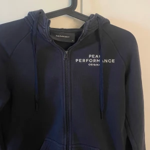 Blå peakperformance hoddie  - Blå hoddie med dragkedja. Storlek XS från peakperformance. Knappt använd så i mycket gott skick