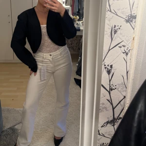 Svart croppad kavaj med rundad kant - Säljer en svart croppad kavaj med rundad, öppen framkant och snyggt diskret mönstrad kant. Jackan har lång ärm och är perfekt för dig som gillar stilrena och moderna plagg. Passformen är normal och materialet känns slätt och lätt. Aldrig använt! Som en  xs/s