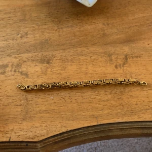 Chunky guldarmband  - Snyggt chunky armband i guld med rejäla, fyrkantiga kedjelänkar som ger en cool statement-look. Perfekt för dig som gillar att sticka ut med accessoarer. Låset är ett klassiskt karbinlås som håller armbandet säkert på plats.