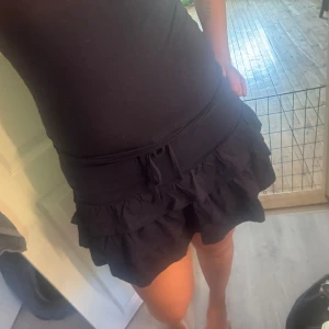 Mörkblå volangkjol med snörning - Supersöt mörkblå minikjol från Gina tricot med volanger och snörning i midjan. Kjolen har en loose passform och är tillverkad i ett lätt bomullstyg. Enkel att styla med både crop tops och hoodies. (Enbart testade men har ingen prislapp kvar). 