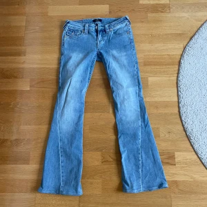 True Religion Joey Low Rise Flare Jeans - Snygga ljusblå jeans från True Religion, modell Joey Low Rise Flare. De har låg midja och utställda ben. Populära och slutsålda på många hemsidor. Uppsydda så att de passar om man är 160-165 cm lång.