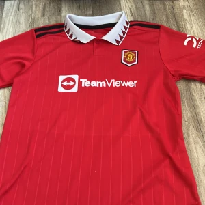 Manchester United Ronaldo 7 matchtröja - Säljer två olika Manchester United fotbollströjor med Ronaldo 7-tryck. Båda är röda med vita detaljer, TeamViewer sponsortryck och klubbmärke på bröstet. En har klassisk krage med mönster, den andra har vit rund hals. Perfekt för dig som älskar United och Ronaldo. 200 för båda. 