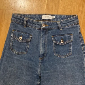 Flare jeans från & Other Stories - Snygga blå jeans från & Other Stories med bootcut-ben, hög midja och flare. Jeansen har två framfickor med lock och knapp, klassisk femficksdesign.