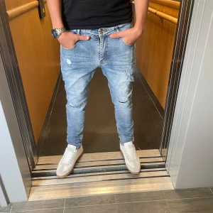 Jeans me slitningar - Säljer ett par tvär feta ljusblå jeans me slitningar. Jeansen är trendiga och prefekt för sommaren. Storleken 32 i midjan och 32 i längd. Vid frågor och funderingar är de bara att höra av sig