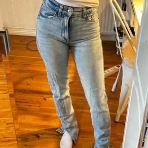 Ljusblå raka jeans med hög midja - Säljer ett par ljusblå jeans med hög midja och raka ben. Jeansen har klassisk femficksdesign, bälteshällor och stängs med knapp och dragkedja. Materialet är denim och passformen är normal med en snygg vintagekänsla.