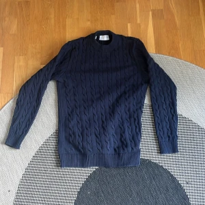 Selected homme tröja - Säljer en stilren mörkblå stickad tröja med rund halsringning. Tröjan har långa ärmar och ribbade muddar vid ärmslut och nederkant. Perfekt för en stilren outfit.