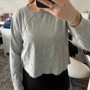 Grå långärmad tröja - Säljer en stilren grå långärmad tröja med rund halsringning. Tröjan har en enkel design med dekorativa sömmar och är perfekt för en avslappnad look. 