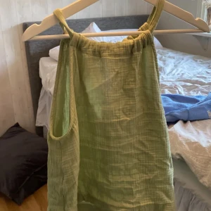 Grön ärmlös topp - Säljer en söt grön ärmlös topp med knytning i halsen. Perfekt för varma sommardagar. Klänningen har en luftig passform och är gjord i ett lätt material.