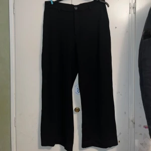 Svarta vida byxor från Lindex - Snygga svarta byxor från Lindex i en vid modell. Tillverkade i en mjuk, stretchig, och bekväm viskosblandning. Perfekta för en stilren look. Köpta hösten 2023 men använda fåtal gånger.