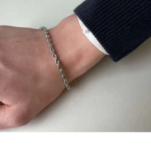 Silverfärgat armband med tvinnad design - Elegant silverfärgat armband med en tvinnad design som ger en stilren look. Perfekt för att komplettera din outfit med en subtil touch av elegans. Armbandet har en säker låsmekanism. Aldrig andvänd men tycker armband stör så mycket på att ah på sig dem.  Den är 19 cm lång. Men priset är inte hugget I sten skriv om du har några frågor eller funderingar!