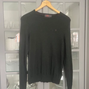 Mörkgrön tröja från Morris - Säljer en stilren mörkgrön tröja från Morris i 100% merinoull. Tröjan har en enkel design med rund hals och långa ärmar, perfekt för kyligare dagar. Den är mjuk och bekväm, idealisk för både vardag och mer uppklädda tillfällen. (Passar XS också).