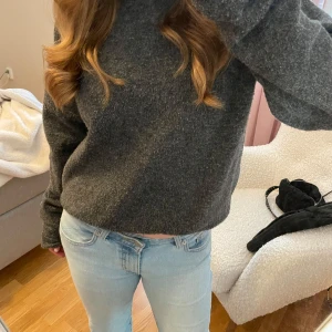 Mörkgrå stickad tröja - Säljer en mysig mörkgrå stickad tröja med långa ärmar. Perfekt för kyliga dagar och enkel att matcha med jeans eller kjol. 