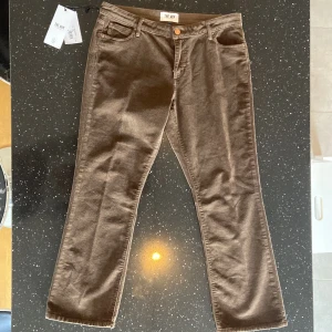 Bruna manchesterbyxor från THE.NIM STANDRAD - Snygga bruna manchesterbyxor från THE.NIM STANDARD med en klassisk design. Byxorna har en normal passform med lite utsvängt längs ner. Jag är 173cm och byxornas längd passar person som är några cm längre än mig. De har en knapp och dragkedja framtill samt praktiska fickor.