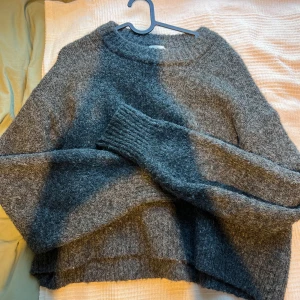 Grå stickad tröja  - Säljer en mysig grå stickad tröja från H&M. Tröjan har en baggy passform med långa ärmar och en rund halsringning. Mjukt tyg och inte alls stickig! Storleken passar alla från M-XL