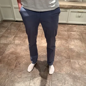 Blå chinos - Snygga blå chinos med normal passform. Perfekta för en stilren look. De har en klassisk design med knappar och dragkedja framtill.