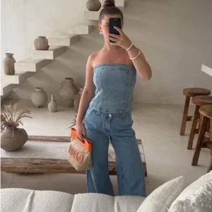 Jeans tubtopp - Snygg jeans tubtopp i klassisk blå denim. Perfekt för en trendig look med en tight passform. Toppen är axelbandslös och har en stilren design som passar till många olika outfits.