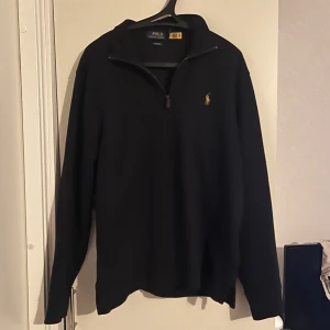 Svart tröja från Polo Ralph Lauren - Svart tröja från Polo Ralph Lauren med dragkedja vid halsen och det klassiska logotypbroderiet på bröstet. Nypris ca 1100 mitt pris 750, aldrig använd. Blandning mellan jättemörkblå och svart 