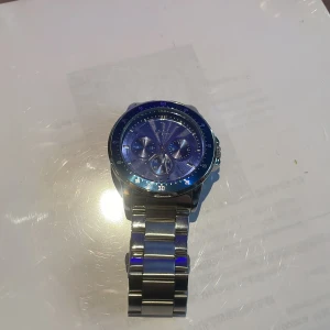 Blå klocka med metallarmband - Snygg klocka med blå urtavla och matchande blå bezel. Klockan har tre mindre urtavlor och ett robust metallarmband. Perfekt för en stilren look. Den är rostfri och farten tät 