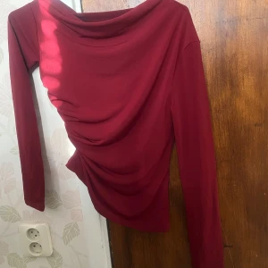 Vinröd långärmad topp - Snygg vinröd topp med draperad design och långa ärmar. Perfekt för en stilren look. Passar bra till både jeans och kjol.