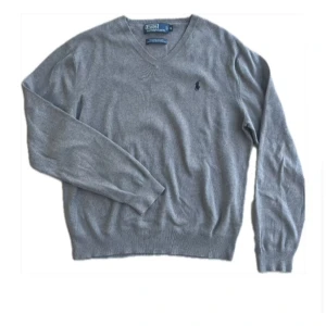 Grå tröja från Polo Ralph Lauren - Säljer en stilren grå tröja från Polo Ralph Lauren i mjuk bomull. Tröjan har en v-ringad design och ett diskret broderat logotypmärke på bröstet. Perfekt för en avslappnad men elegant look. Storlek M. Ny pris=2000kr men jag säljer min för 500kr