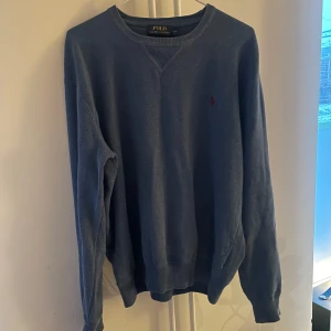 Blå tröja från Polo Ralph Lauren - Säljer en stilren blå tröja från Polo Ralph Lauren i 100% bomull. Tröjan har en klassisk design med rund hals och långa ärmar. Perfekt för en avslappnad look.