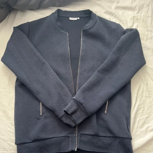 Mörkblå zip up tröja från J.Lindeberg - Snygg mörkblå tröja från J.Lindeberg. Väldigt bra skick, knappt använd.