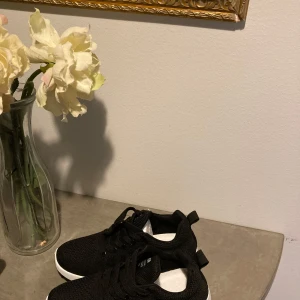 Svarta sneakers med vit sula - Snygga svarta sneakers med vit sula och snörning. Skorna har en stickad ovandel som ger en modern look och bra andningsförmåga. Perfekta för en avslappnad stil. Helt nya, aldrig använda. 