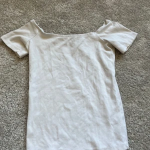 Vit offshoulder topp från Gina Tricot - Säljer en stilren vit offshoulder topp från Gina Tricot. Toppen har korta ärmar och är perfekt för en avslappnad look. Passar bra till både jeans och kjol. Perfekt för varma dagar💕
