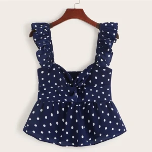 Blå prickig topp med volangdetaljer - Snygg blå topp med vita prickar och volangdetaljer på axelbanden. Toppen har en söt knytdetalj framtill och är perfekt för sommarens varma dagar.