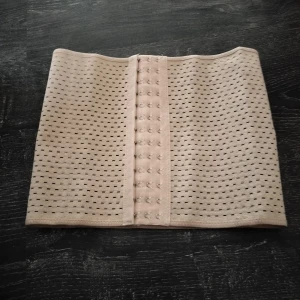 Beige waisttrainer korsett large - Snyggt beige med perforerat mönster och hyskknäppning framtill. Perfekt för att ge extra stöd och stil till din outfit. Korsetten är elastiskt och anpassar sig efter din kropp för en bekväm passform och för att se smalare ut Storlek Large 