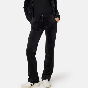 Svarta Juicy Couture byxor  - Snygga svarta Juicy med snörning i midjan. Byxorna har en bekväm passform och bakfickor med knappar. Perfekta för en avslappnad stil.