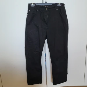 Svarta byxor från Amalia - Snygga svarta byxor från Amalia med klassisk design. Byxorna har en rak passform och är utrustade med både fram- och bakfickor. Perfekta för en stilren look. Insydd resårband i bakre delen av byxorna för snug passform