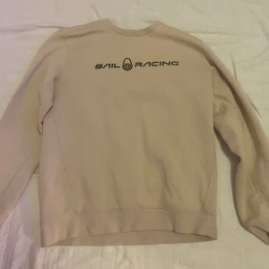 Beige tröja från Sail Racing - Säljer en stilren beige tröja från Sail Racing. Tröjan har en enkel design med långärmade ärmar och en rund halsringning. Perfekt för en avslappnad stil.