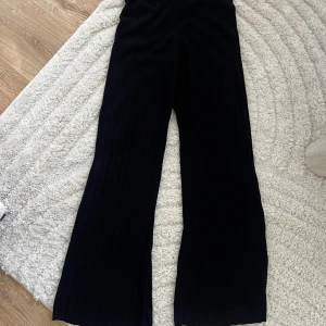 Svarta ribbade byxor - Snygga svarta byxor med ribbad textur. Byxorna har en loose passform och är perfekta för en stilren look. De är tillverkade i ett mjukt material som ger en bekväm känsla hela dagen.