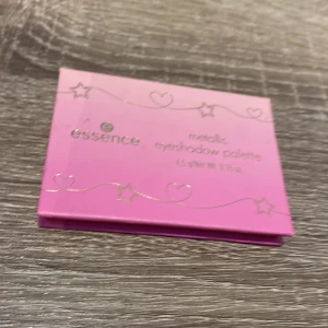 Essence Metallic Eyeshadow Palette och Rouge - Säljer en metallic ögonskuggspalett från Essence med sex olika nyanser, inklusive glittriga och matta toner. Perfekt för att skapa en gnistrande look. Inkluderar även en rouge i en livlig rosa nyans med glittrande detaljer.