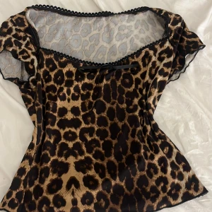 Leopardmönstrad blus med spetsdetaljer - Snygg leopardmönstrad blus med korta ärmar och spetskant vid halsringningen. Blusen har en liten rosett framtill säljer för att den inte kommer till användning 🩷