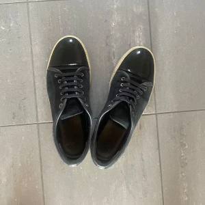 Svarta sneakers från Lanvin - Snygga svarta sneakers från Lanvin med glansig tå och snörning. Perfekta för en stilren look. Skorna har en klassisk design med en modern twist.