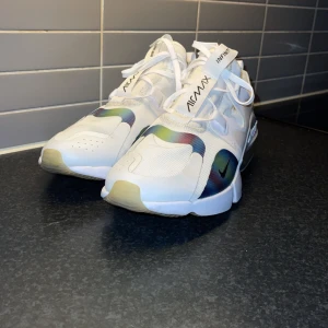 Nike Air Max Infinity sneakers - Snygga Nike Air Max Infinity sneakers i vitt med färgglada detaljer. Skorna har en modern design med synlig Air Max-dämpning och snörning för en bekväm passform. Perfekta för både stil och komfort.