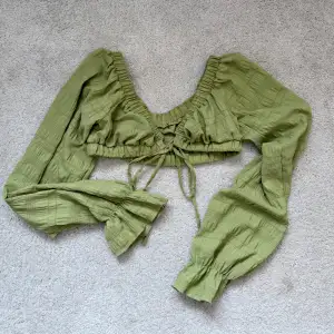 Säljer en söt grön långärmad topp med knytning framtill och långa ärmar. Toppen har en rynkad design och är perfekt för en somrig look. Den är croppad och har en fin passform.