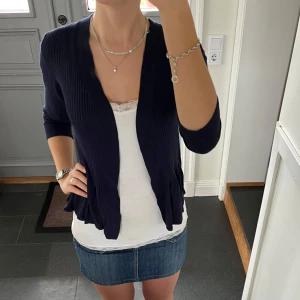 Blå stickad kofta  - Mörkblå finstickad kofta med volanger i storlek S från Kathy Ireland. Fint skick. Använd gärna köp nu!